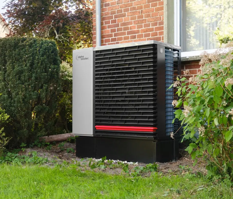 Air source heat pump fitted outside a brick house