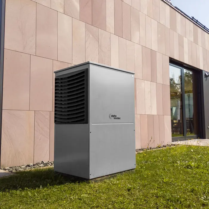 An air source heat pump on a lawn beside a modern extension