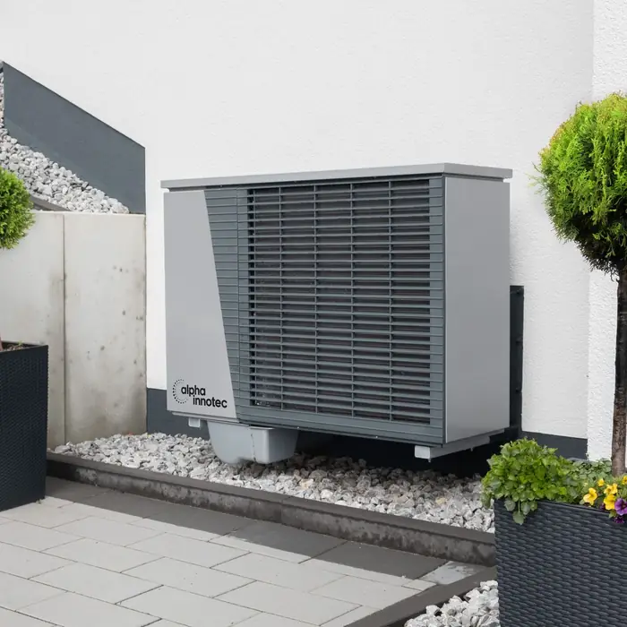 An air source heat pump on a patio beside potted plants